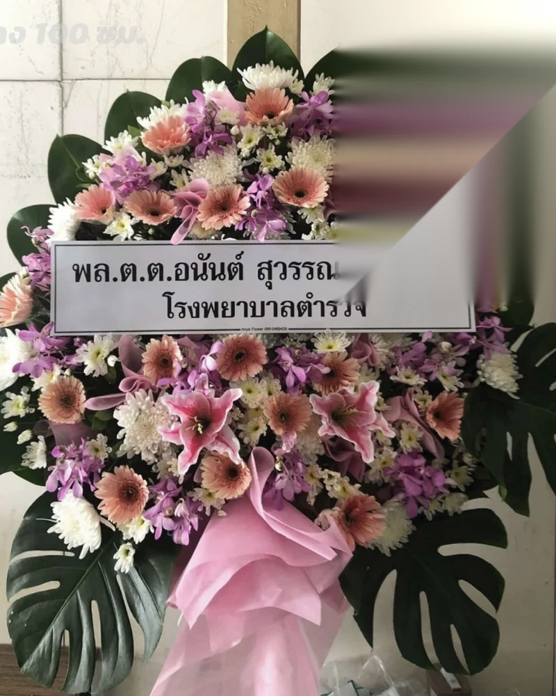 พวงหรีดดอกไม้สดตั้งอยู่หน้าศาลาวัดในกรุงเทพฯ ช่วงเย็นที่มีรถแขกงานศพจอดเรียงแน่นด้านนอก